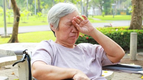 Asian senior woman has sleepy expression,female elderly yawning covering open mouth with hand,old people feel yawn,doze,sleepy in outdoor park,being tired after sleepless night,lack of sleep concept