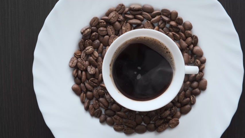 cup of coffee on a plate with coffee beans