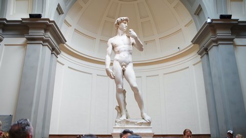 Firenze, Italy - August 30, 2018: Panning people inside or indoors of famous Florence Accademia art museum gallery looking at David statue of Michelangelo