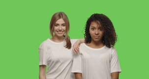 two beautiful girls posing and smiling on chroma key background . Happy multiracial women having fun on a Green Screen, 4k video footage slow motion 60 fps