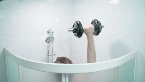 Bodybuilding while taking a shower 4K. Medium shot above the shower cabin with person arm in focus while lifting weights.