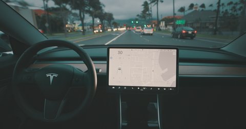 MAUI, HAWAII - January 19, 2020: A Tesla Model 3 driving with the latest self driving software update in town traffic, the future of self driving vehicles is here