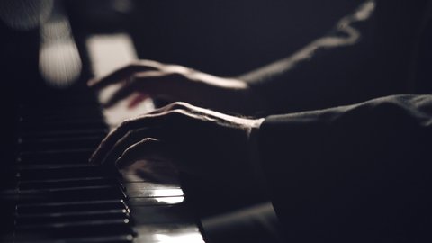 Man two hands plays gentle classical music on a grand piano. Professional pianist