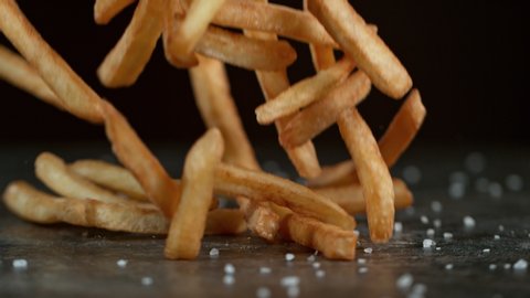 Super Slow Motion Shot of Falling Fresh French Fries on Black Table at 1000fps.