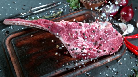 Super Slow Motion Shot of Falling Fresh Tomahawk Meat and Seasoning on Cutting Board at 1000 fps.
