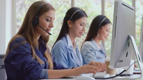 Customer support agent or call center with headset works on desktop computer while supporting the customer on phone call. Operator service business representative concept. – Stockvideo