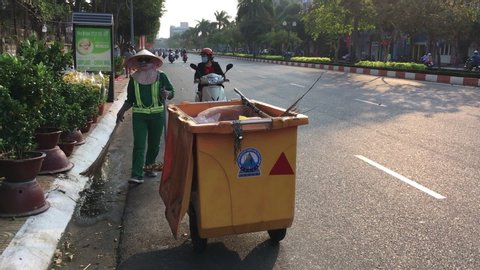 VUNG TAU, VIETNAM - JUNE 10, 2015: An unidentified street cleaner sweeps the roadside on Tet's Eve - Vietnamese Lunar New Year.
