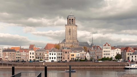Aerial cityscape with parallax effect of the Deventer city facade seen from the river IJssel in The Netherlands against a dramatic afternoon cloudy sky with boat passing by