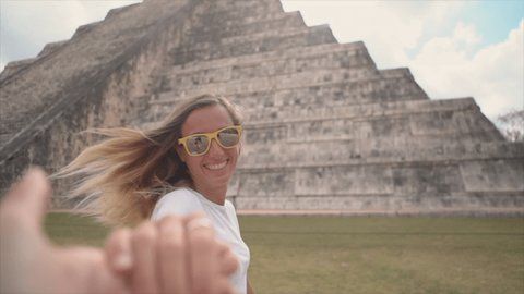 Follow me to concept, couple holding hands at Chichen Itza in Mexico. People travel concept, man's personal perspective of following girlfriend. woman leading man. Slow motion 