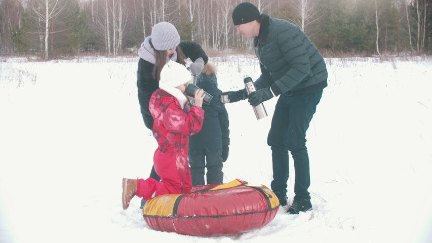 Family drinking tea from the termos outdoors near the forest