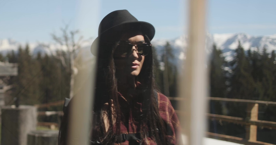 Slow motion, window relfection footage of a beautiful brunette caucasian female taking of her sunglasses and looking intently at her reflection