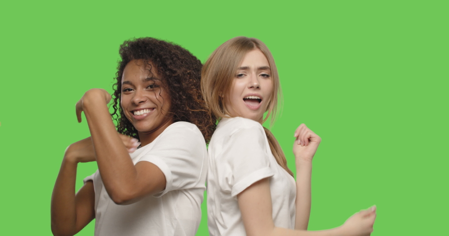 Two beautiful girls dancing and smiling on chroma key background . Happy women having fun on a Green Screen, 4k video footage slow motion 60 fps