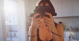 An young woman is using innovative technology vr glasses for play boxing workout in a kitchen in a morning. Shot in 8K. Concept of future, innovation, technology, gaming,lifestyle, entertainment