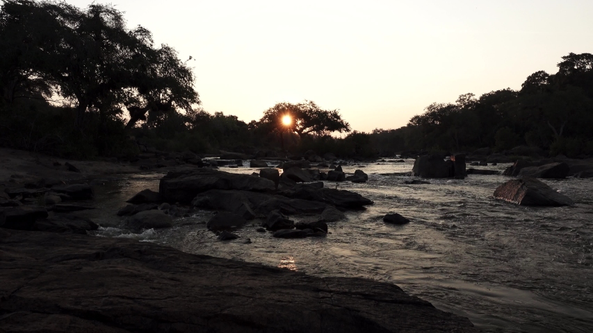 Loopable sunset over river with sun behind shinning the tree