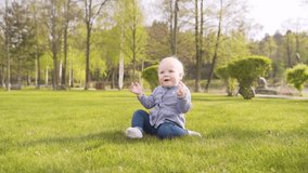 Baby girl playing outdoor, spending day on green lawn in park