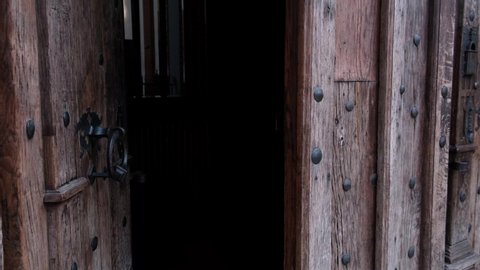 Close-up of closing old wooden door with metal handle in ancient medieval Catholic church. For religion, histotic, architecture background.