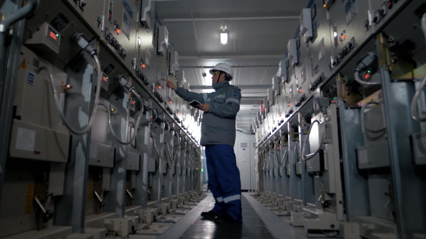 The working electrician controls the operation of the switchboard at a power plant with modern equipment Royalty-Free Stock Footage #1045550005