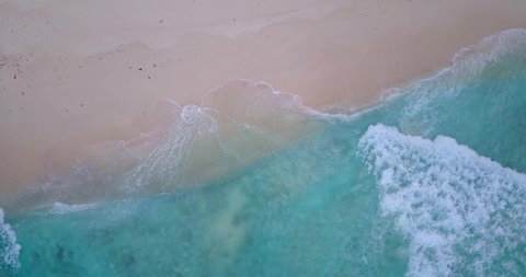 Beautiful sea shore texture with untouched fine sand washed gently by white waves of clear turquoise water of lagoon, copy space