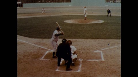 1970s: Rear view of batter at plate. Runner on base. Pitcher winds up. Rear view of batter, image freezes. Pitcher throws. Batter hits. Players running. Player runs bases. Player throws to base.