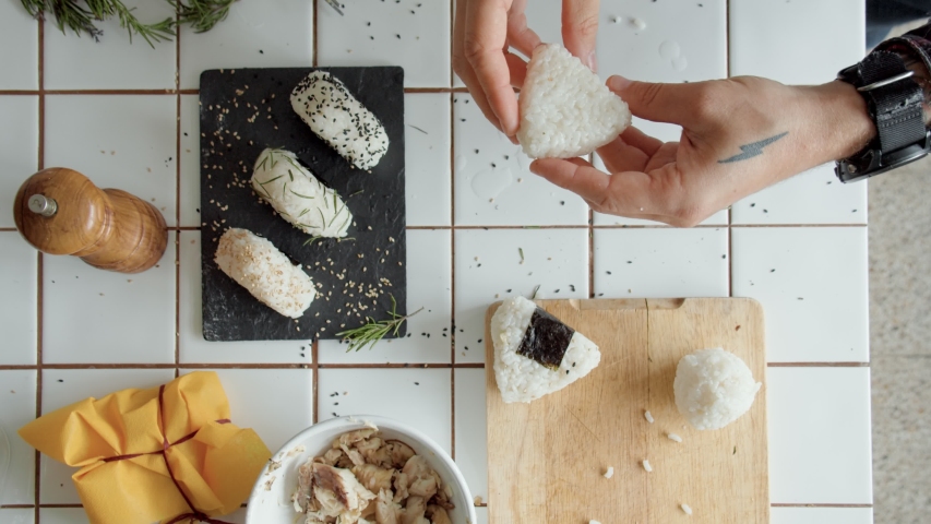 Top view man prepares onigiri. Chef makes healthy vegeterian japanese snack. Lunch to go food. Healthy cooking at home from internet blog recipe