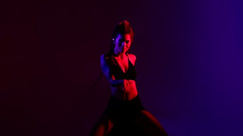 Black dressed and braided hair woman dancing on a blue and red background.	