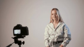 happy female records video with photo camera attached to tripod. young cute blond girl filming tutorial vlog about makeup, smiling, applying cosmetic tonal foundation. Beauty blogger, content creator