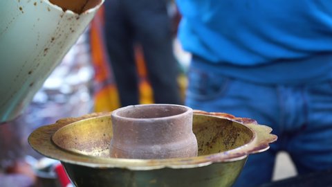 Indian street food vendor making tandoori masala chai tea by boiling in a hot clay pot in brass pot to boil the tea giving up clouds of steam. This milk tea is a popular drink in India especially the