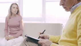 cropped view of mature psychologist writing prescription while talking to patient
