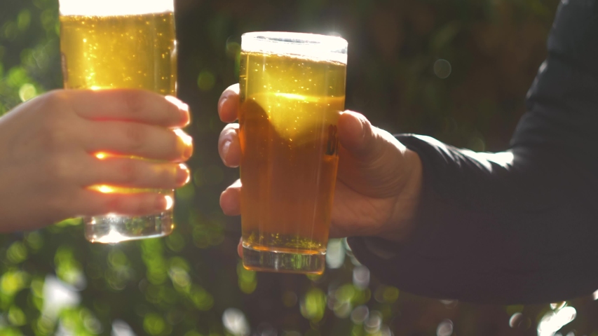 Celebration beer cheers concept - close up hands holding up glasses of beer of people group in outdoor party during their victory competition or successful task meeting vacation