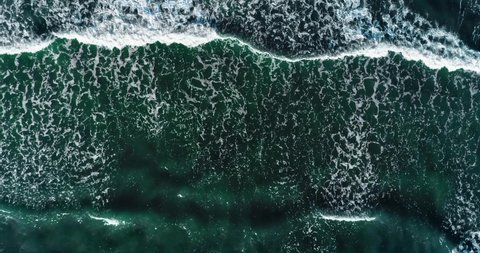 Top down aerial view of giant ocean waves crashing and foaming. UHD. Slow motion