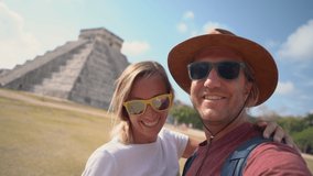 Cute lovely couple taking selfie video chat  using mobile phone, self portrait in front of famous ancient Mayan pyramid in Mexico. Two people traveling in Mexico 