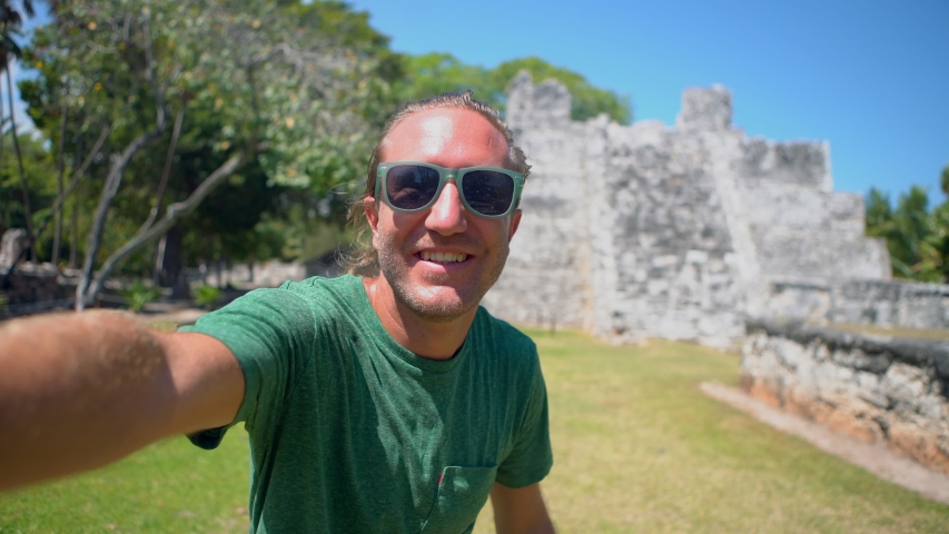Cool man taking selfie video with ancient temple in Mexico sharing travels and moments with camera and friend. Young man selfie sightseeing Mexico 