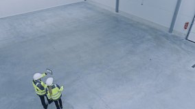 Two Engineers Talking, Walking Across Empty Factory Floor, Inspecting, Planning Where All the Machinery Would go.Professionals Industrial Designers Strategizing about New Manufacturing Plant Design - Powered by Shutterstock - Get 15% off with code: PIKWIZARD15