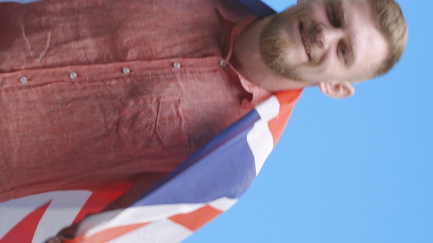 Vertical shot of a young man dancing and holding up the Union Jack
