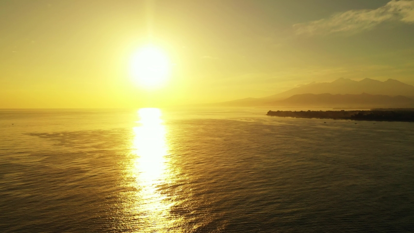 The Beautiful Setting Sun Over The Calm Waters Of The Bahamas With Mountains And A Small Island In The Background - Aerial Shot