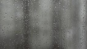 Closeup view of wet glass of window and nasty weather outdoors. Wet snow and rain falling down simultaneously.
