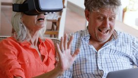 Animation of network and data sharing icons with a close up of a senior Caucasian couple laughing and using technology in the background, the woman wearing a VR headset and the man using a laptop - Powered by Shutterstock - Get 15% off with code: PIKWIZARD15