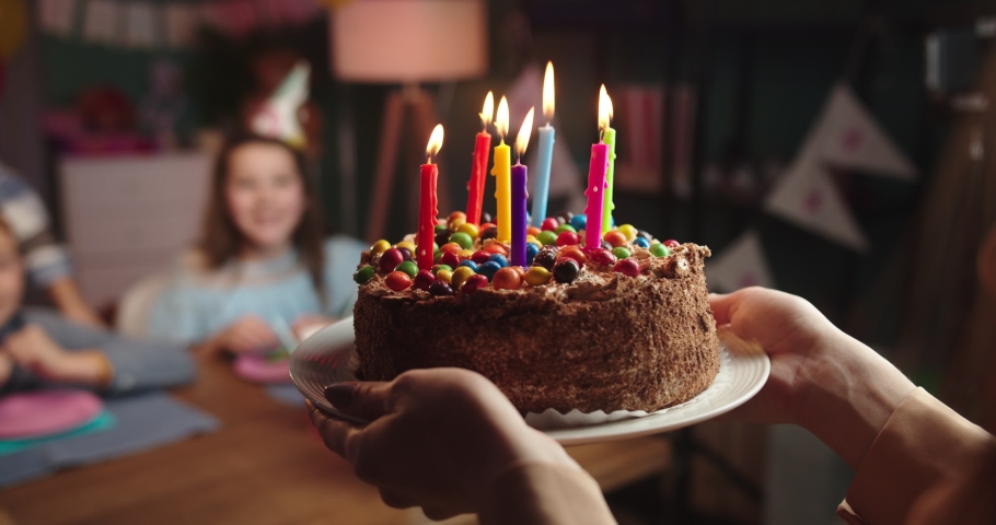 Close up of the birthday cake with candies and candles in hands of the woman while she bringing it to his small cute son for birthday party. Royalty-Free Stock Footage #1045653316