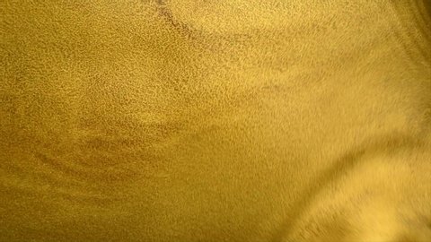 Liquid gold abstract background. Flowing Golden abstract backdrop. Beautiful metallic yellow texture. old metallic paint with a brush close-up. Liquid gold Art Wallpaper. 4K UHD slow motion