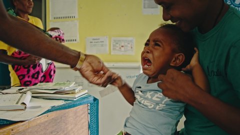 Melsisi, Pentecost Island / Vanuatu - May 10 2019: remote village medical nurse doctor injects vaccine to a small child kid at a local hospital dispensary at an isolated island location