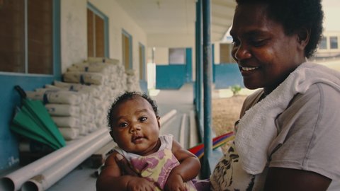 Melsisi, Pentecost Island / Vanuatu - May 10 2019: traditional black melanesian woman mother with her cute kid child at waiting at the local village health center hospital