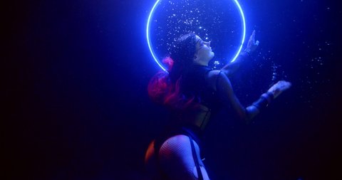 sexy woman in erotic suit is moving slowly underwater in unusual nightclub