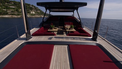 On board view of a luxury boat, with red sofas and nice wooden tables
