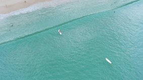 Aerial view 4K video tourists playing surfboard on the green sea at surin beach Phuket Thailand 