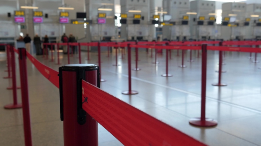 4k interior selective focus static shot of red tape with a line of empty airport departure check in counters with a few people in the blurred background. Royalty-Free Stock Footage #1045681108