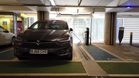 HEATHROW AIRPORT, LONDON - MARCH 16, 2019: An electric Tesla Model S vehicle charges while parked inside the short stay car park at Terminal 5 Heathrow International Airport in London, UK.