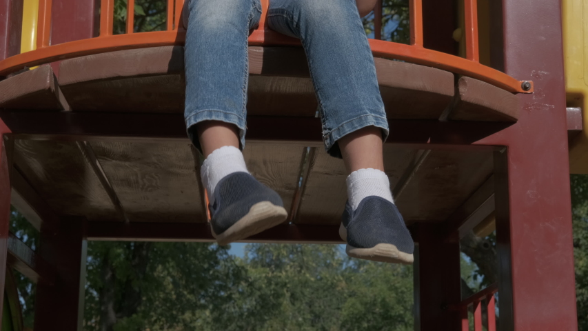 Healthy game on playground. A view of a nice child sitting on a kid place in sunny light.