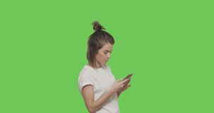 Girl reading text message on her mobile phone over green screen background, chroma Key 4k raw video footage slow motion 60 fps