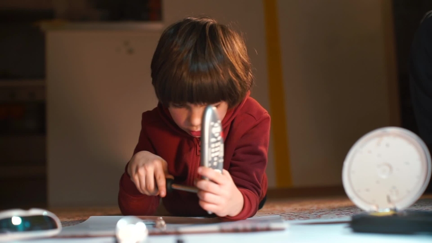 The child makes repairs to the remote control from the TV. Turns the screws with a screwdriver.