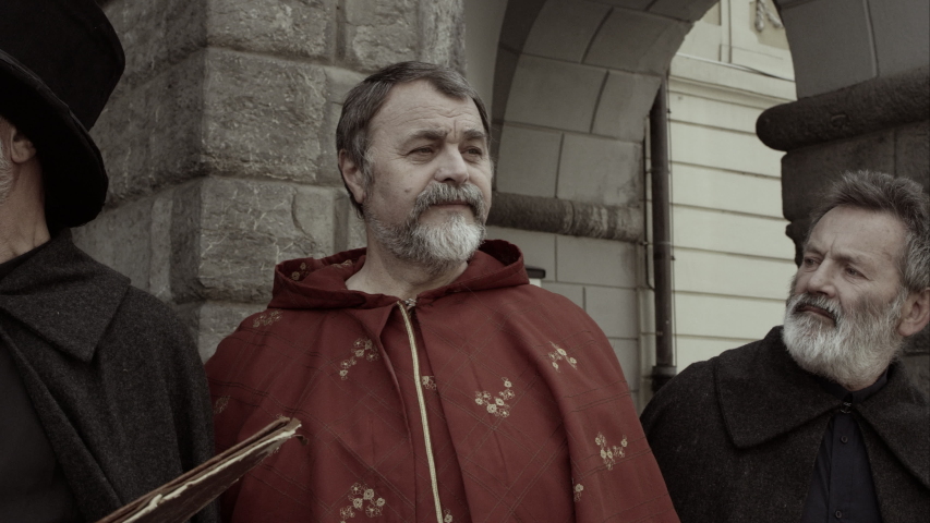 Three Men In Front Of Town Building Make Exasperated Gestures At Somebody